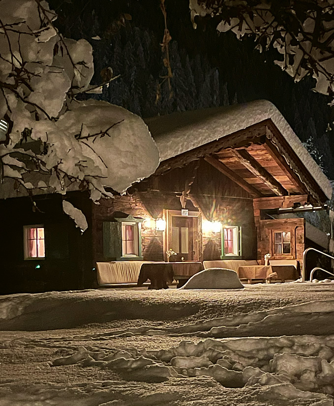Foto von Tirolerhof Neustifts Pool Hütte im verschneiten Garten stimmungsvoll beleuchtet im Winterabend
