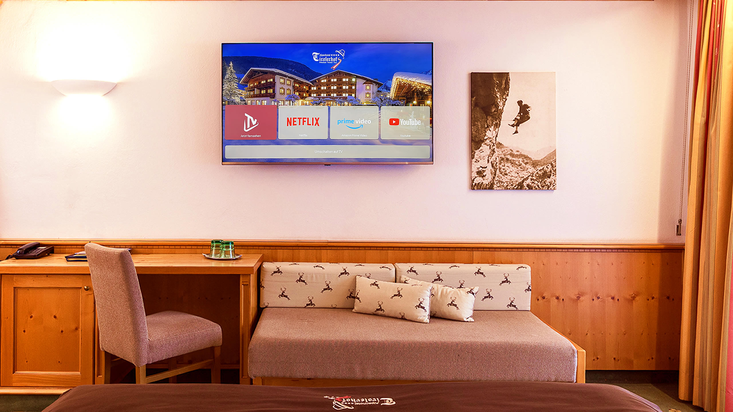 Zimmerbild StreamingImage Winter Foto: Tirolerhof Zimmerimagebild mit Sitzcouch, 55 Zoll Smart-TV mit Hotelinfokanal und Streaming-Apps wie Netflix, Amazon und YouTube (einfach per QR-Code in deinem Account einloggen, streamen und sicher automatisch ausgeloggt werden),
